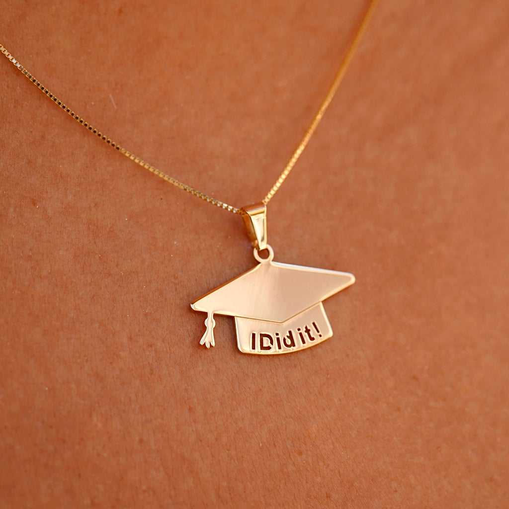 A model elegantly wears the 14K solid gold graduation cap pendant on a delicate chain, showcasing its brilliant shine and meaningful design. The charm rests beautifully against the skin, making it a perfect way to commemorate this special milestone.
