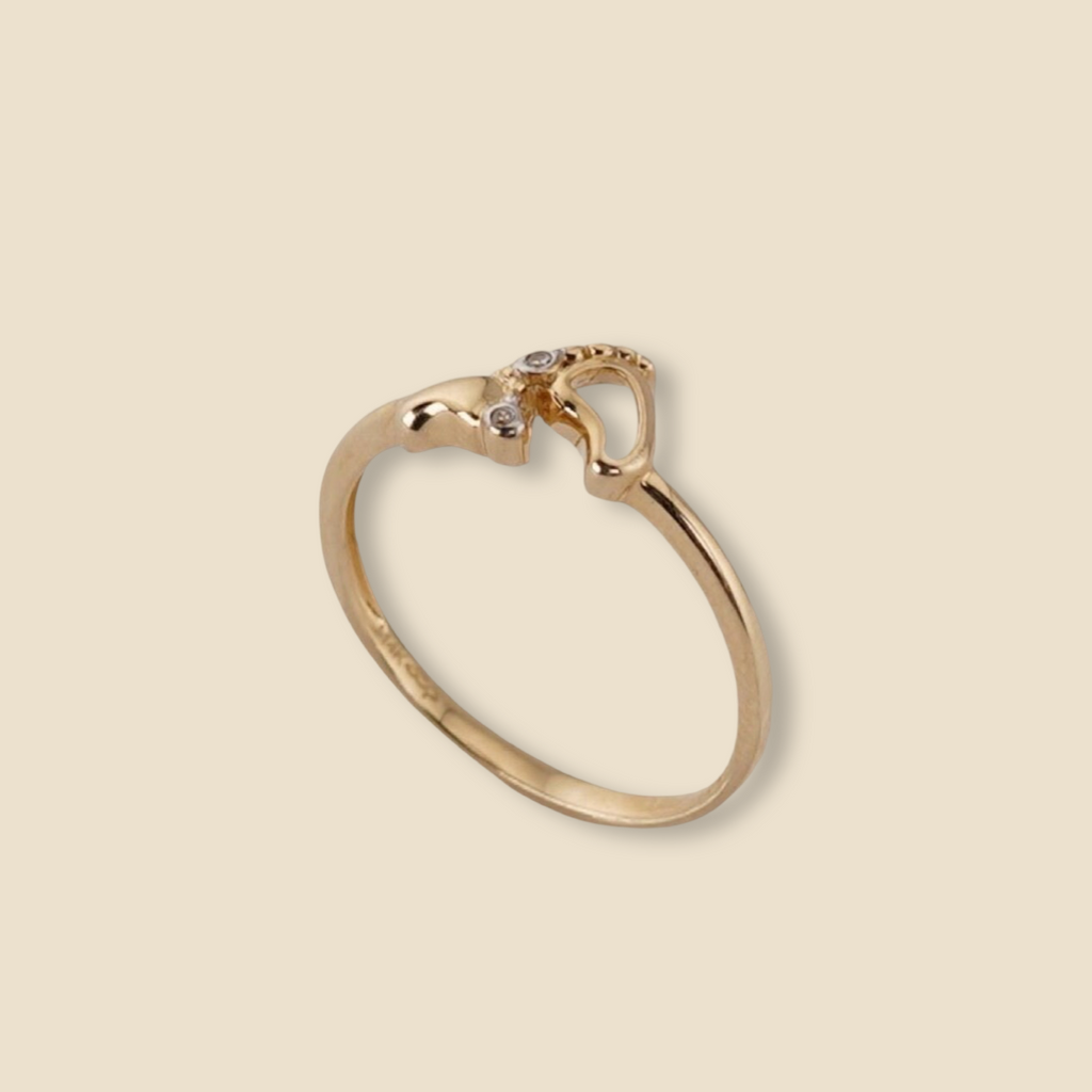 Close-up of the 14K Gold Baby Feet Ring resting on a plain background, showcasing its fine detailing and soft golden glow.