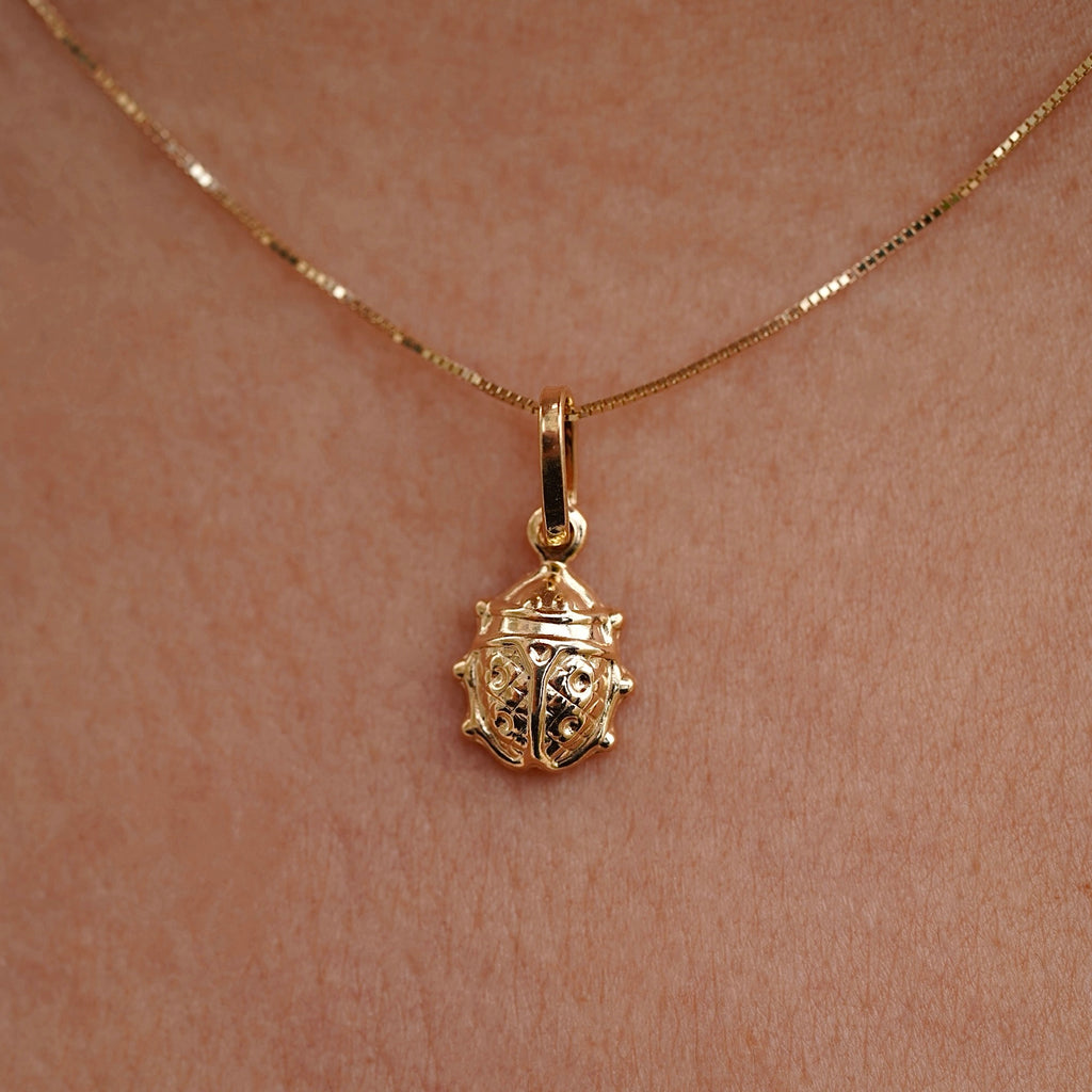 Close-up of a model gracefully displaying a 14K gold ladybird charm necklace, highlighting the miniature ladybug design as a symbol of luck and joy.