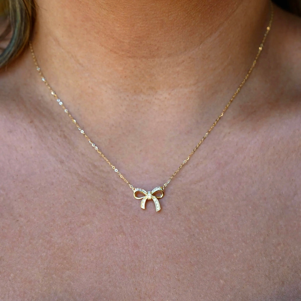 Model wearing the 14K gold ribbon necklace, capturing its dainty charm and graceful fit around the neckline.