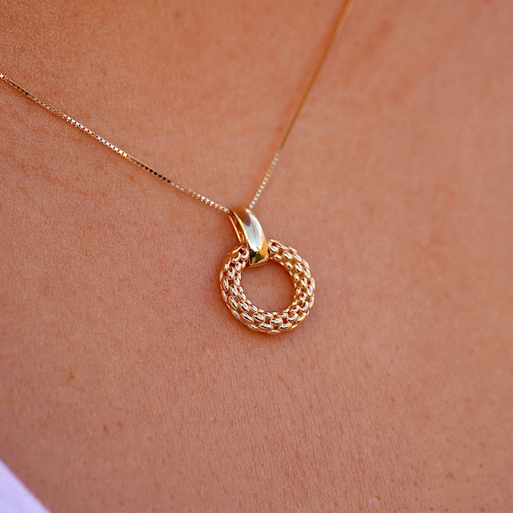 A woman wears the 14K gold mesh pendant on a dainty gold chain, the intricate filigree design resting gracefully against her collarbone. The lightweight and elegant pendant adds a timeless touch to her outfit.