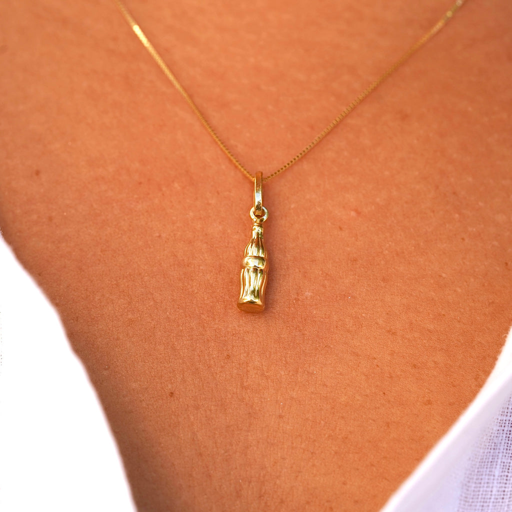 A close-up of a model wearing the 14K solid gold soda bottle pendant on a delicate chain, emphasizing its dainty and playful charm.