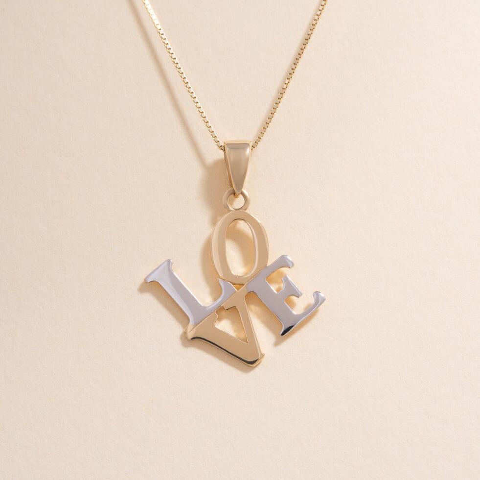Minimalist image of a two-tone 14K gold "Love" charm on a plain background, emphasizing the polished surface and artistic script styling.