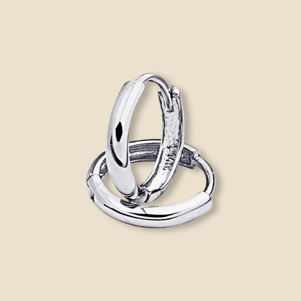 Minimalist 14K white gold Huggies earring photographed against a plain background, emphasizing its compact 8mm size and modern simplicity.