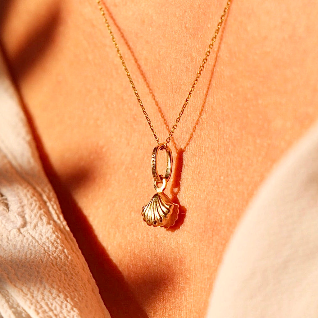 A woman elegantly wearing the 14K Solid Gold Pearl Pendant on a delicate gold chain, highlighting its timeless beauty and sophisticated design against her neckline.