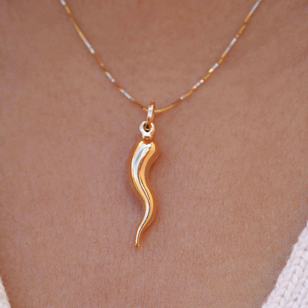 A model wears the 14K Yellow Gold Hollow Horn Pendant on a delicate chain, the pendant’s sleek, polished design resting gracefully on their chest. The hollow horn charm symbolizes protection and strength, adding a touch of elegance and spiritual significance to their look.