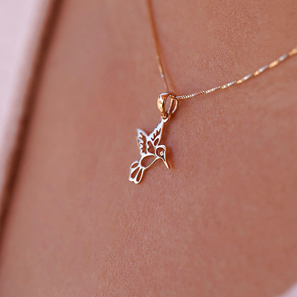 A model elegantly wears the 14K Yellow Gold Hummingbird Pendant on a delicate chain, highlighting its dainty size and the joyful charm it adds to her everyday style.