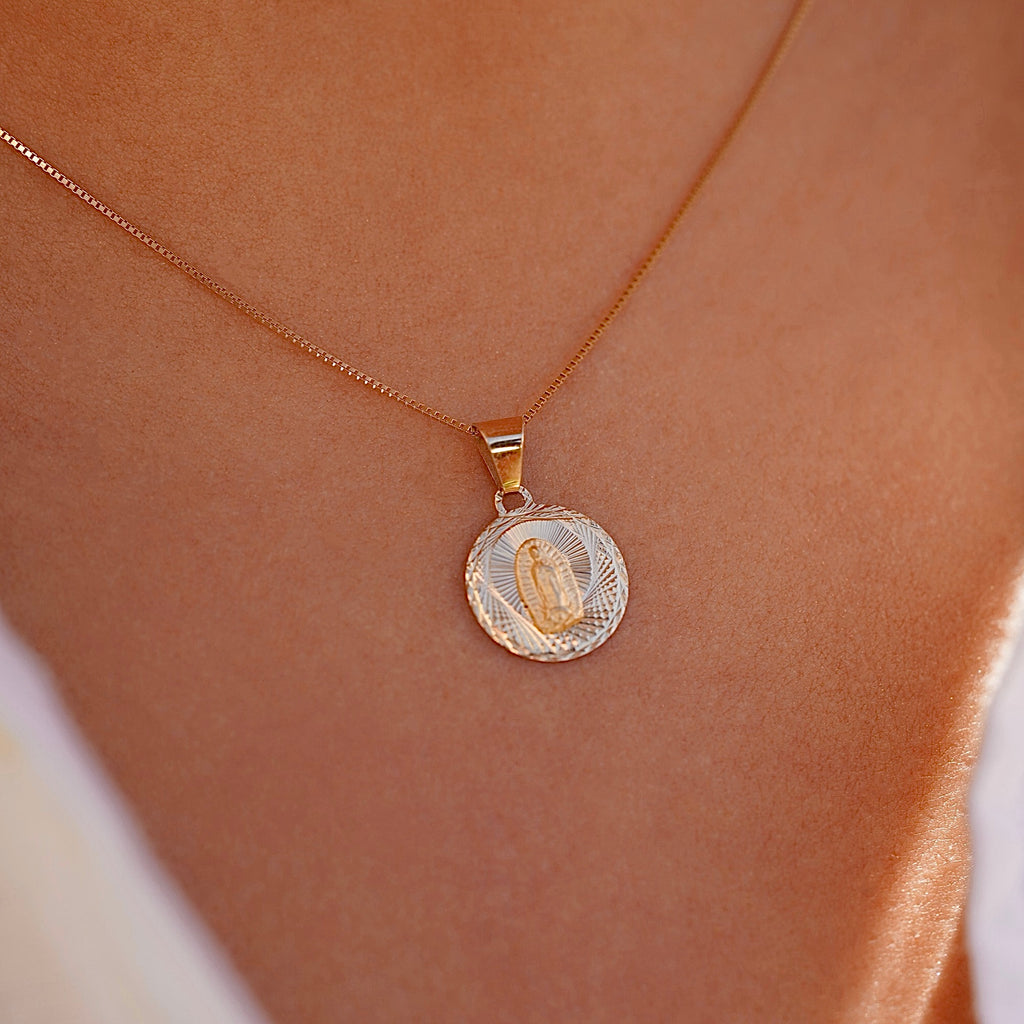 A model wears the 14K gold religious stamp pendant on a fine chain, the charm resting gently near the collarbone, blending timeless faith with everyday elegance.