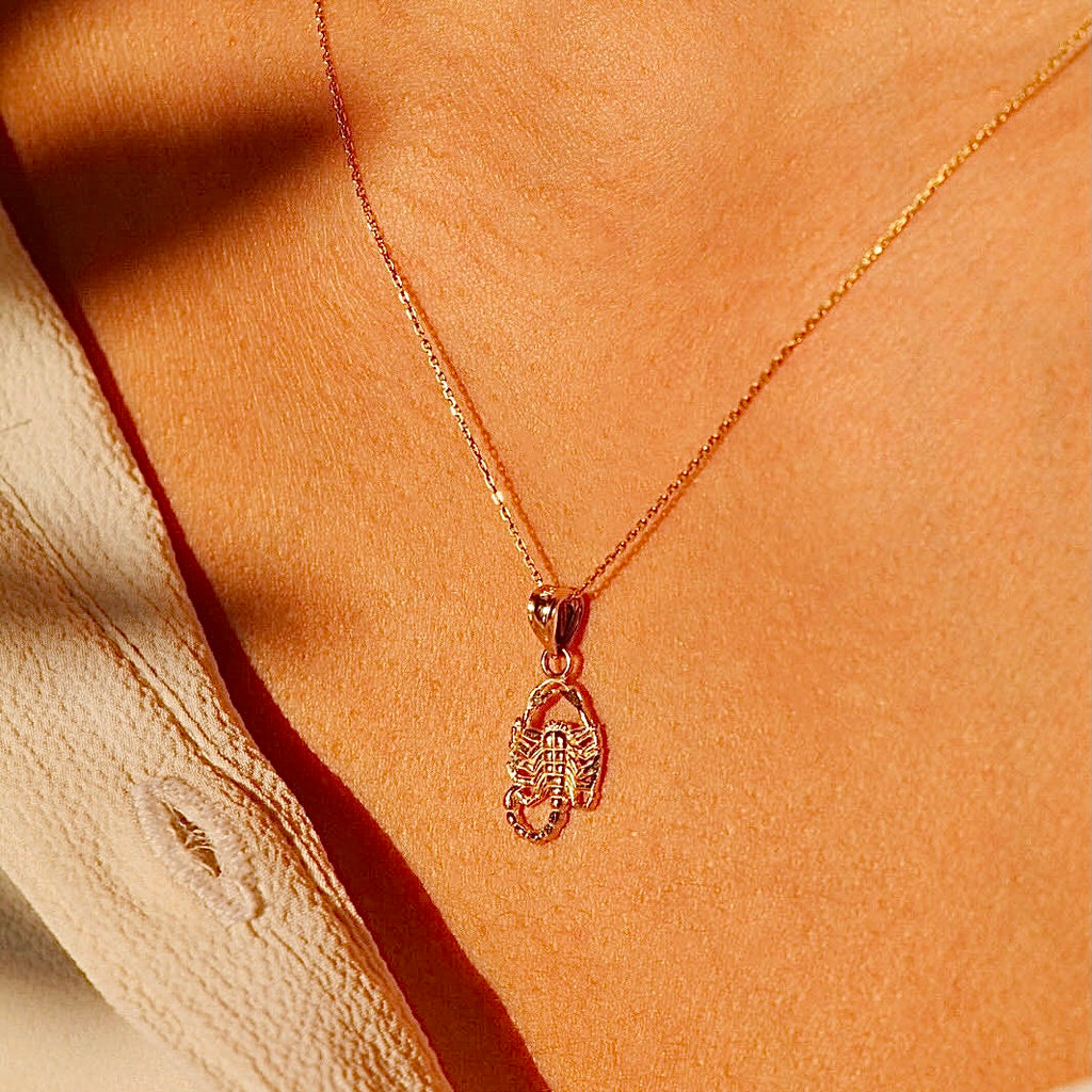 A close-up of a model wearing the 14K gold scorpion pendant on a delicate chain, emphasizing its elegant yet bold presence as a symbolic zodiac piece.