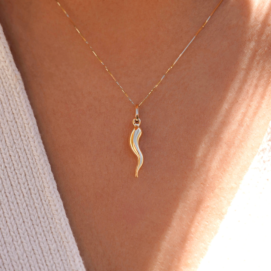 A model wearing a 14K yellow gold hollow horn pendant on a delicate chain, styled with a simple blouse for a minimalist and elegant everyday look.