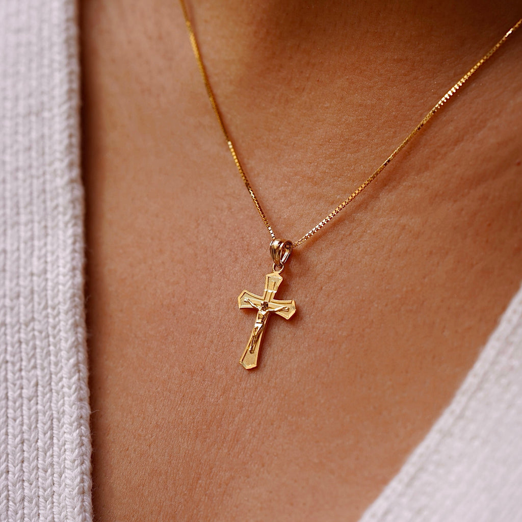 A model wearing the 14K Yellow Gold Crucifix Cross Pendant on a gold chain, highlighting its religious significance and elegant craftsmanship.
