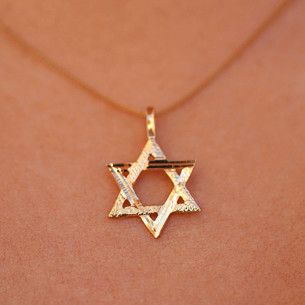 A model wearing the 14K Gold Star of David Pendant on a delicate gold chain, with the pendant resting near their collarbone, adding a subtle touch of faith and elegance to their look.