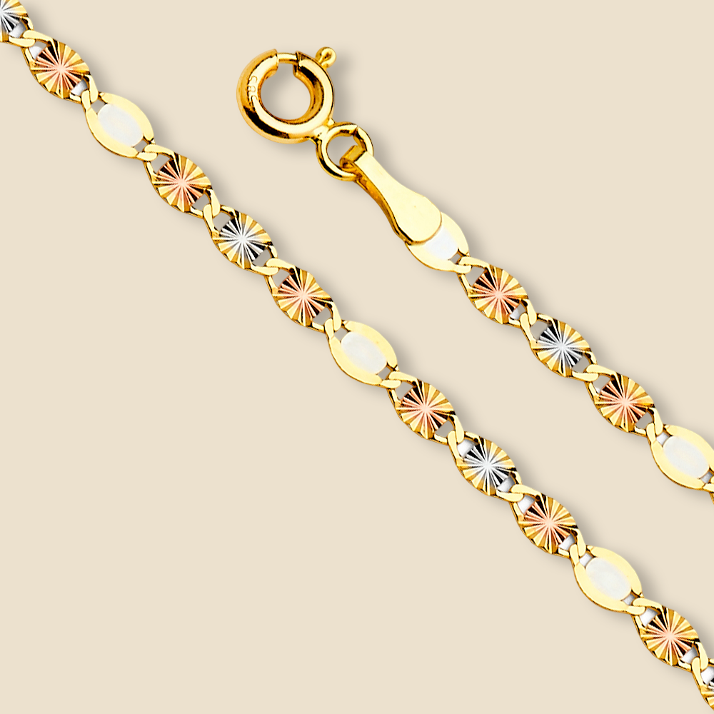 Flat 14K tri-color Valentino star chain necklace laid in a straight line on a plain background, highlighting the shine and elegant diamond-cut star links.