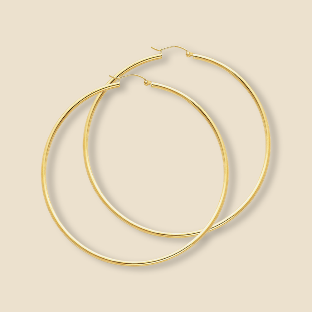 A pair of 14K yellow gold hoop earrings with a high-polish finish, displayed on a plain background, showcasing their smooth, round tube design and 65mm large size.