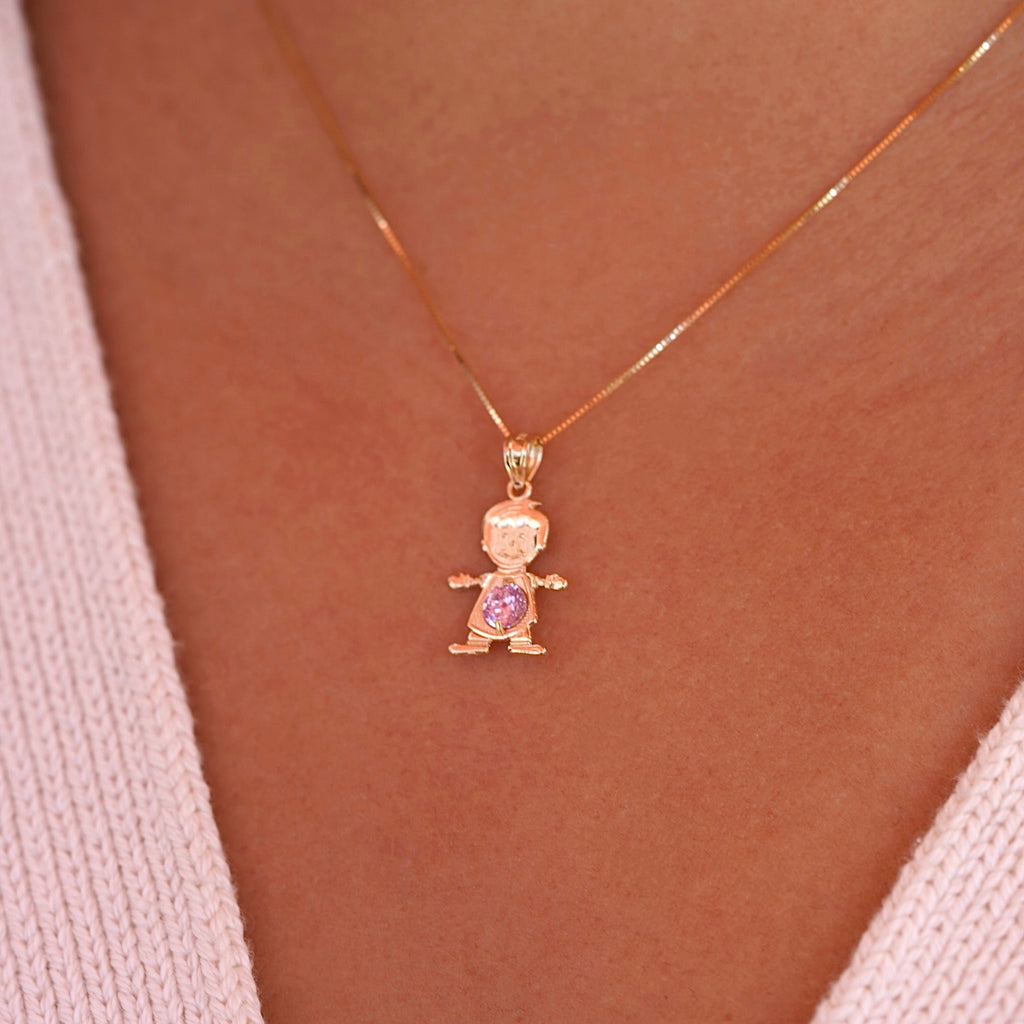A model wearing the October birthstone boy charm on a delicate gold chain, showing how the 14K gold pendant sits lightly near the collarbone with the pink CZ sparkling subtly in the light.