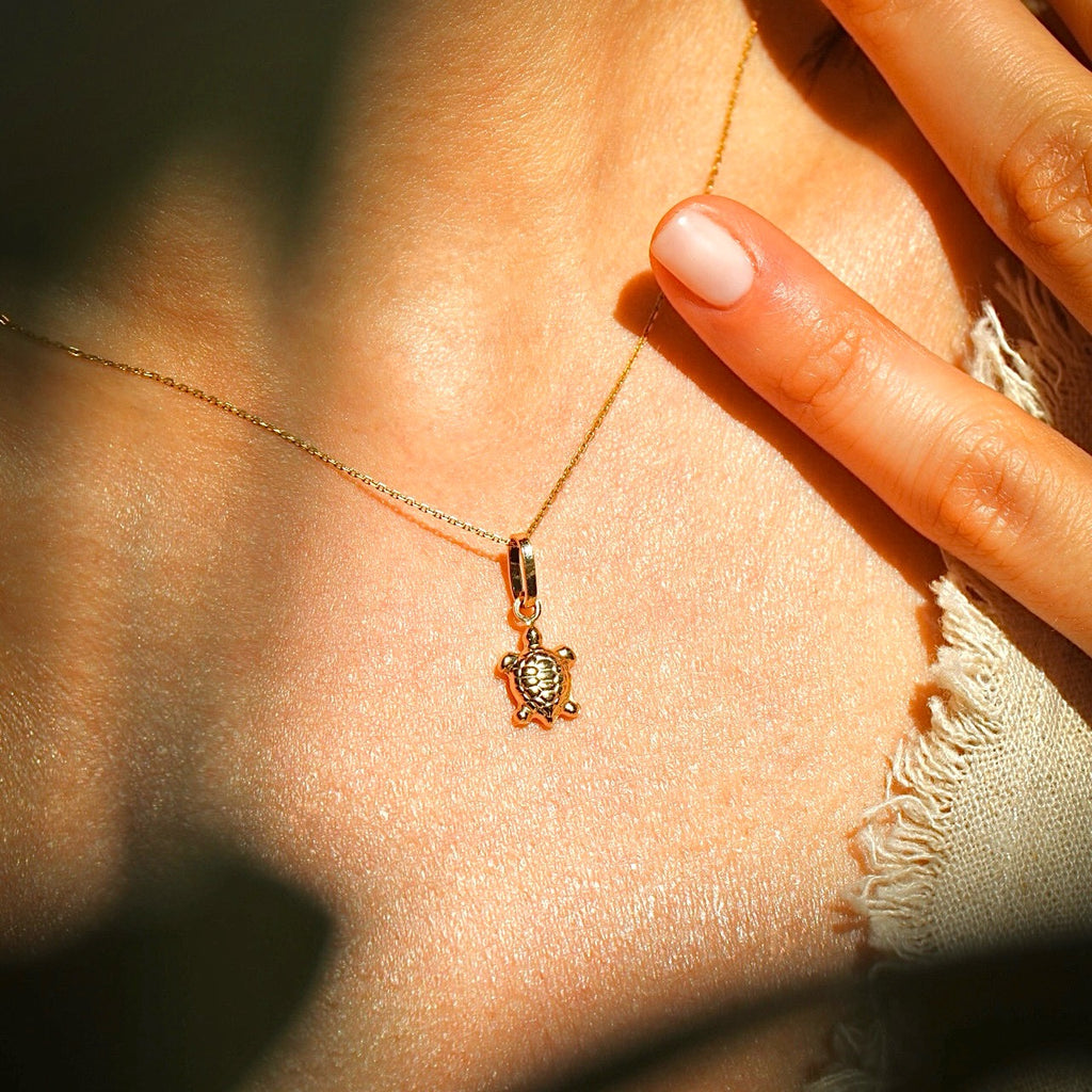 A woman wearing a dainty 14K gold turtle pendant on a delicate chain, highlighting its elegant design and perfect size for everyday wear.