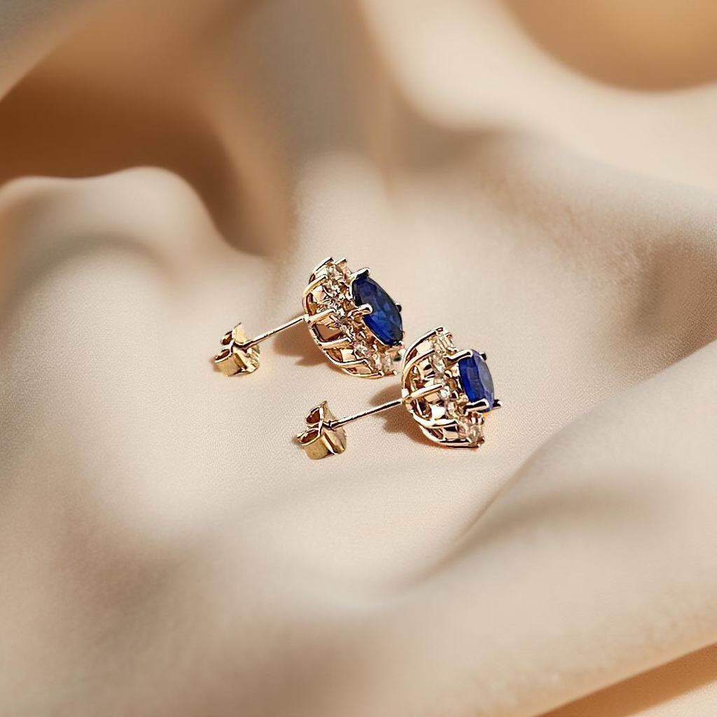 Side view of 14K yellow gold blue stone earrings displayed on soft, off-white linen fabric, showcasing the subtle profile and elegant curve of the setting.