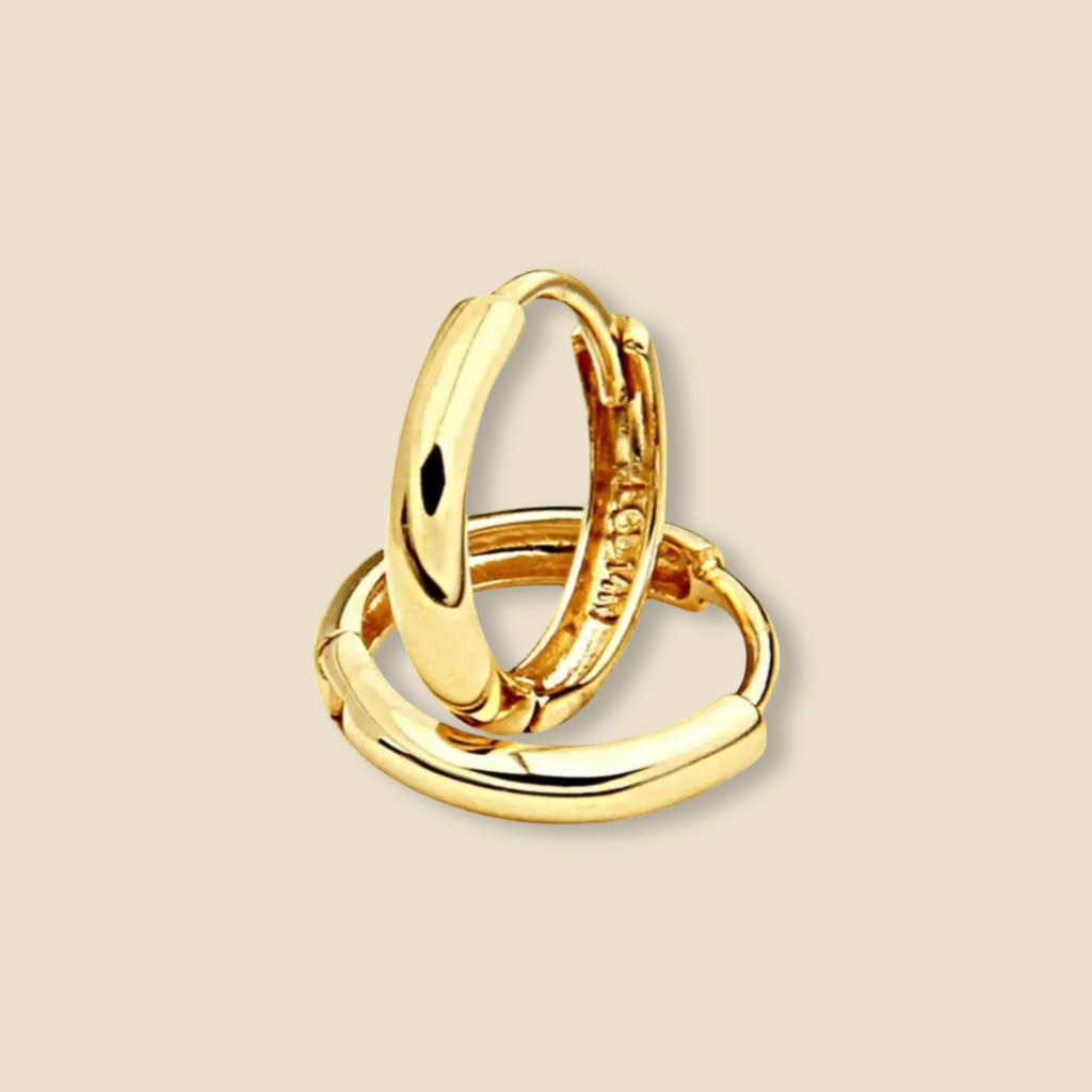 Minimalist 14K yellow gold Huggies earring photographed against a plain background, emphasizing its compact 8mm size and modern simplicity.