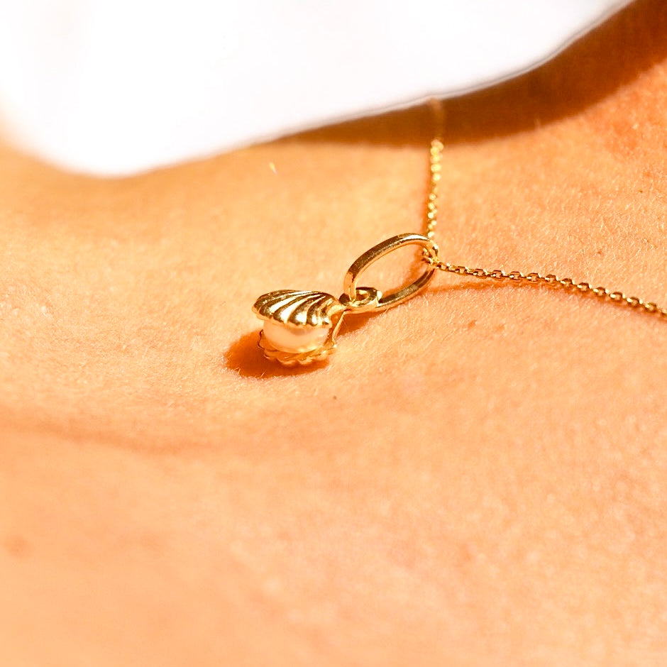 A woman elegantly wearing the 14K Solid Gold Pearl Pendant on a delicate gold chain, highlighting its timeless beauty and sophisticated design against her neckline.