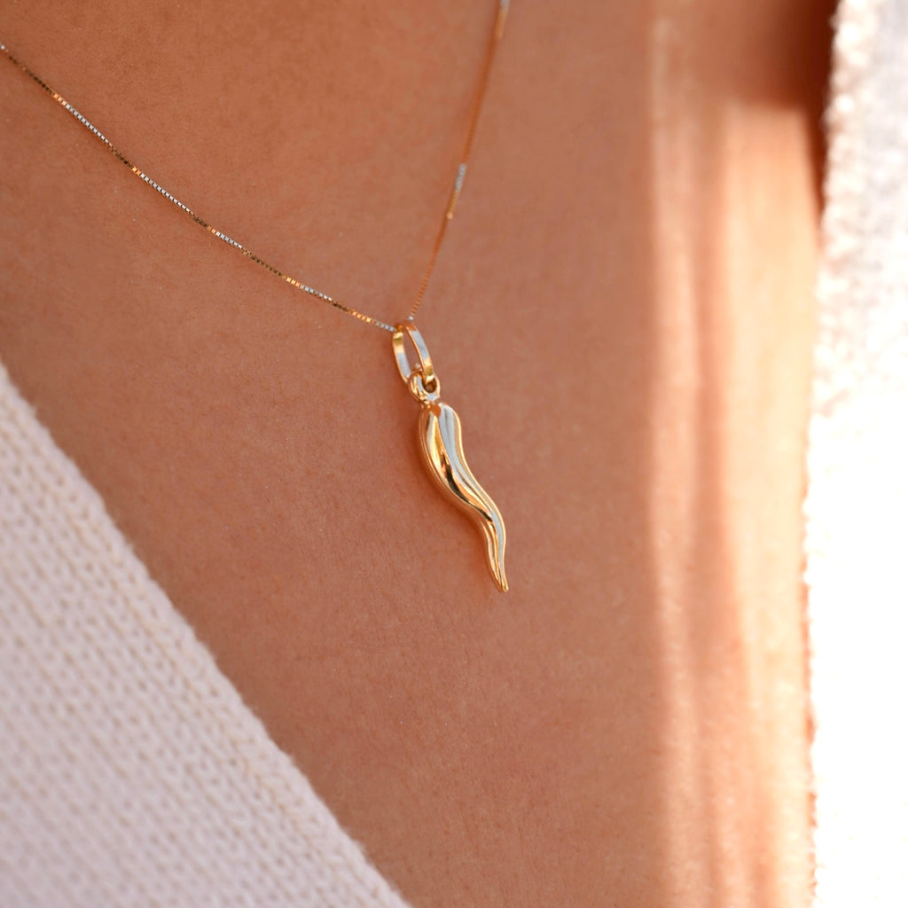 A model wearing a 14K yellow gold hollow horn pendant on a delicate chain, styled with a simple blouse for a minimalist and elegant everyday look.
