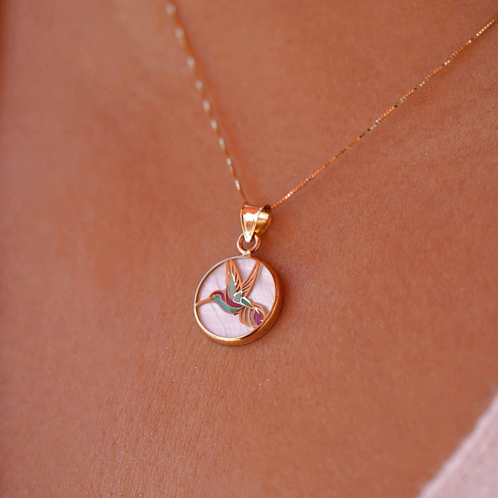 Model wearing the 14K Yellow Gold Hummingbird Medal Pendant on a delicate chain, showcasing the vibrant Mother of Pearl backdrop.