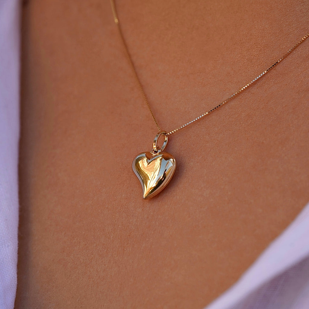 A model wearing the 14K Yellow Gold Hollow Heart Pendant on a fine chain, elegantly styled against her collarbone, highlighting its minimalist beauty.