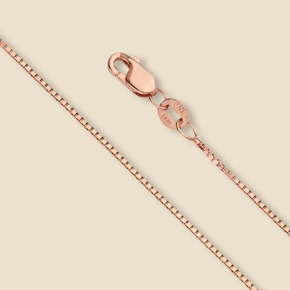 Studio image of a 14K gold box chain in rose, laid straight on a plain background to emphasize its sleek 0.8mm design.