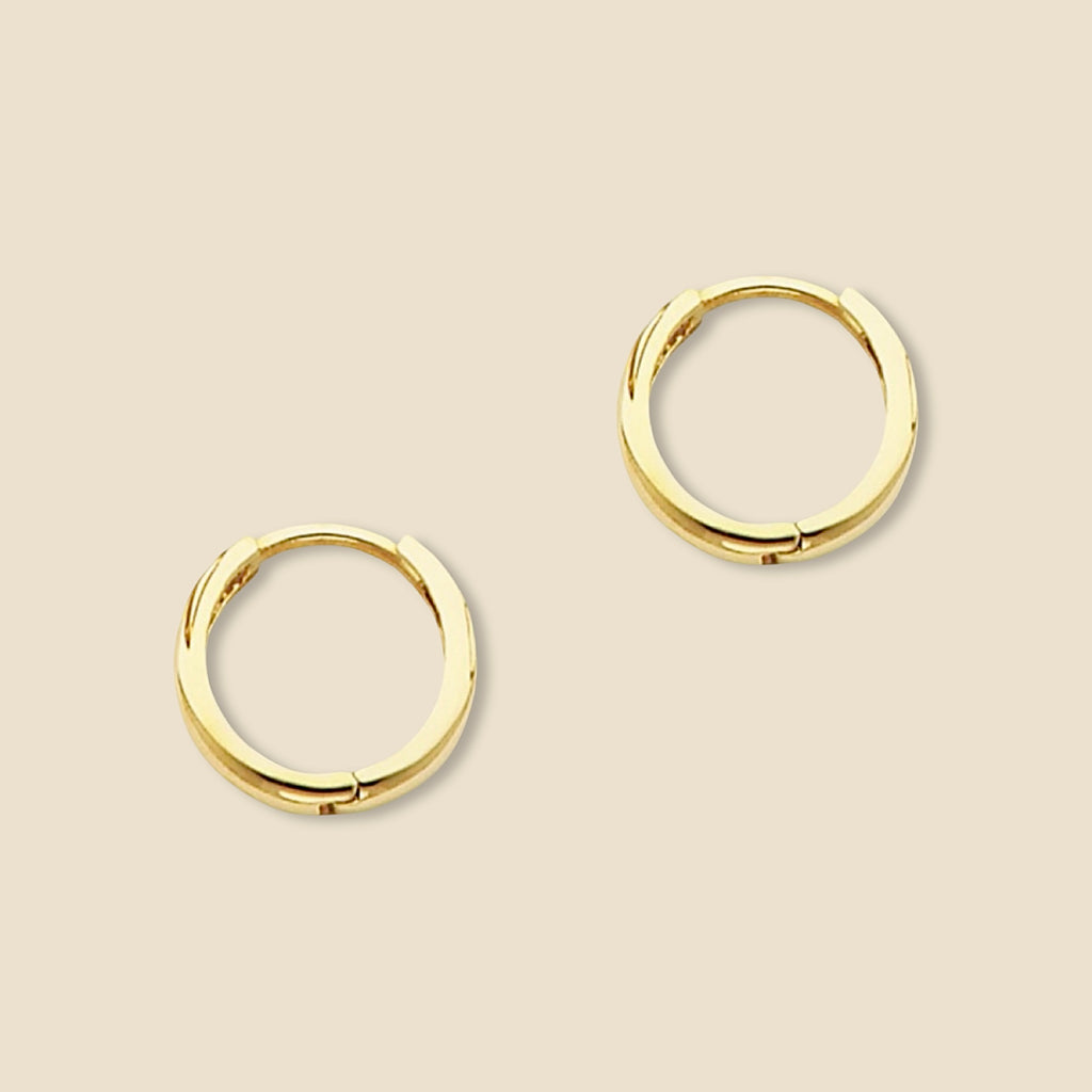 A pair of small 14K yellow gold Huggies earrings shown against a plain backdrop, revealing the sleek curvature and 10mm diameter of each hoop.