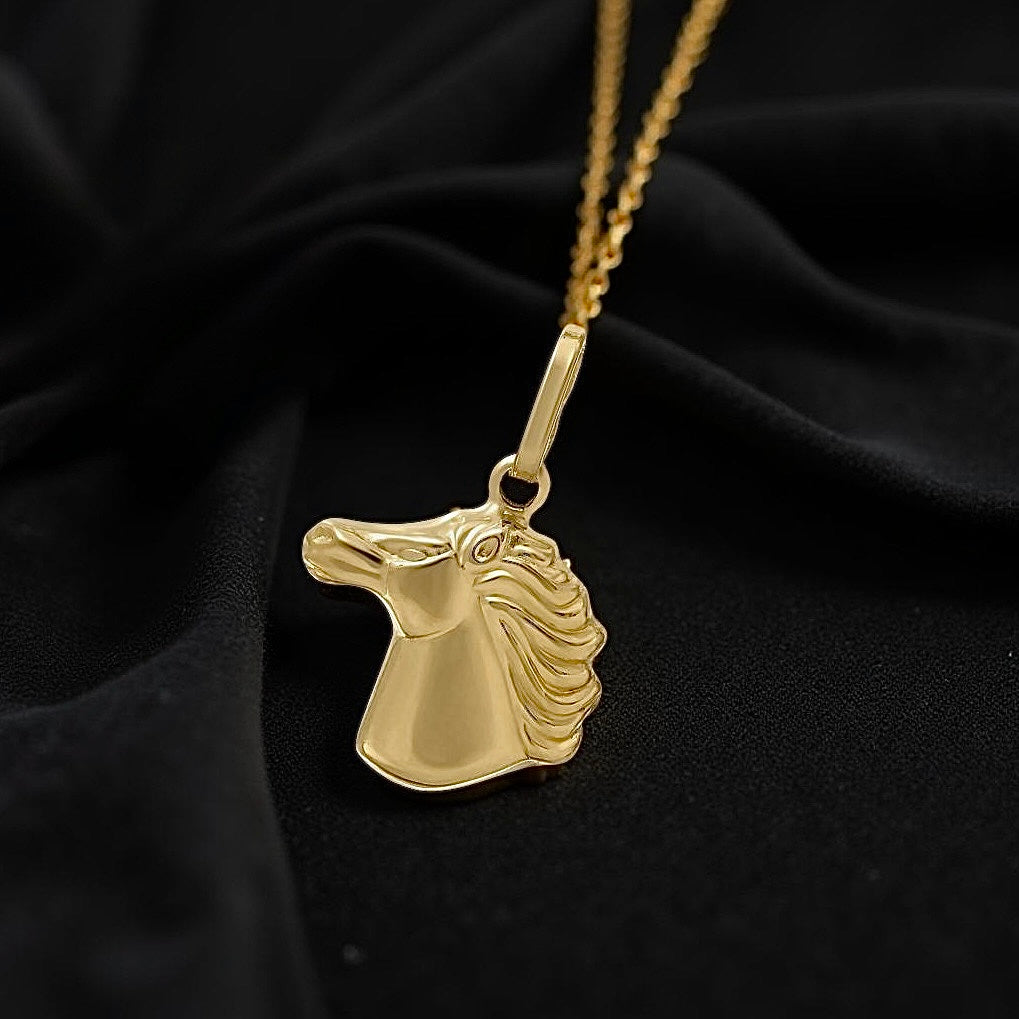14K gold horse head pendant resting on black velvet cloth with natural lighting, highlighting its dainty and elegant design.