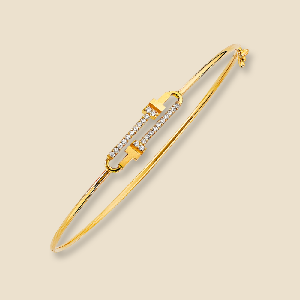 Minimalist CZ flexible bangle in 14K yellow gold placed on a plain background, highlighting its elegant form and polished finish.