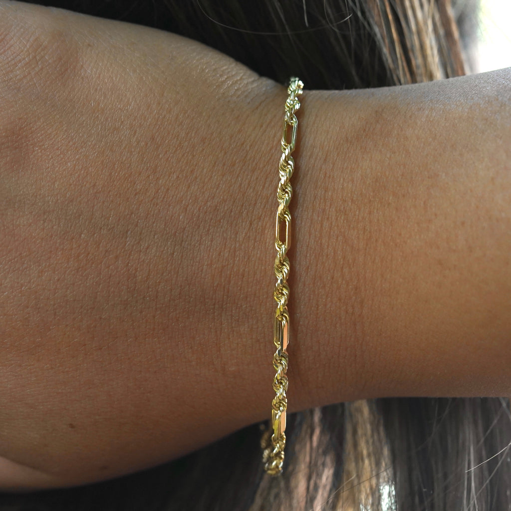 Model wearing a 14K gold Figaro rope bracelet on wrist, demonstrating its dainty yet sophisticated appeal as a daily luxury accessory.