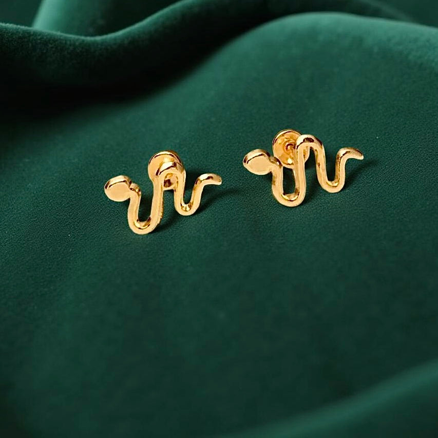 14K Gold Snake Stud Earrings displayed on luxurious green velvet fabric, highlighting their polished shine and elegant design.