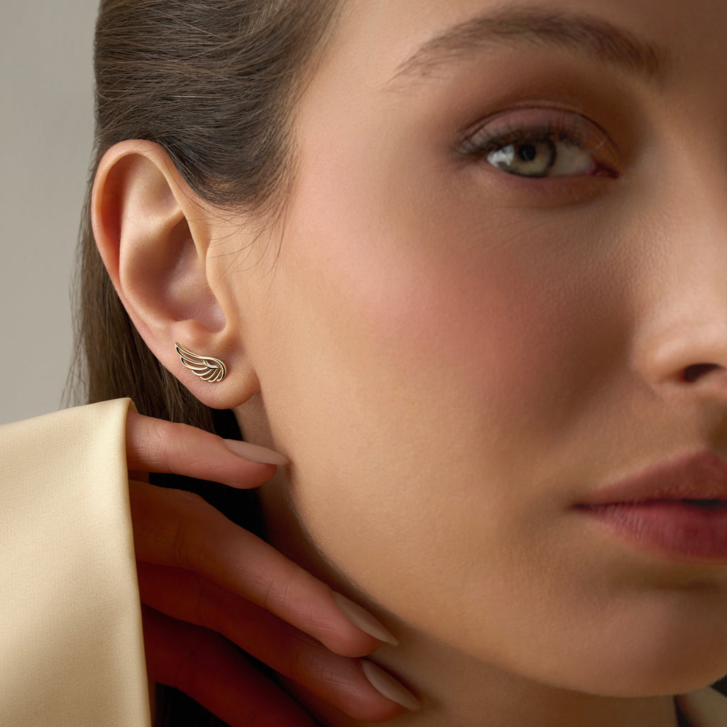Model wearing 14K yellow gold wing stud earrings, showing how the delicate design adds a touch of elegance and symbolism to her look.