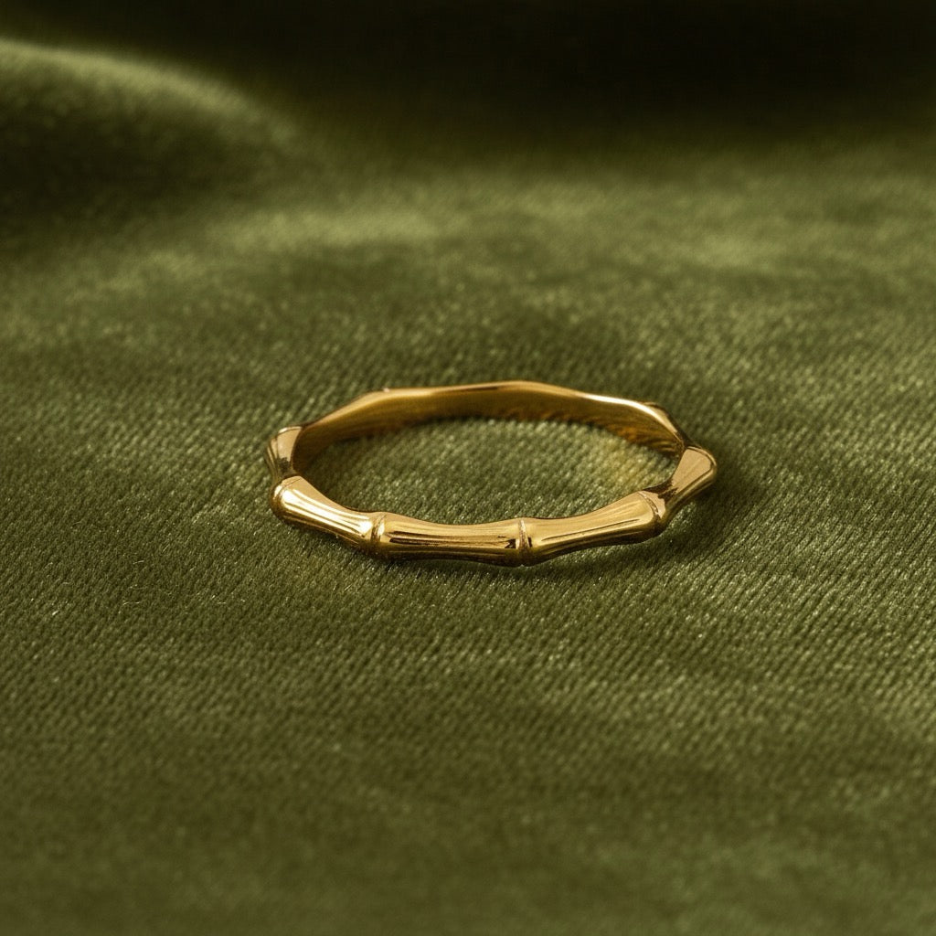 14K Yellow Gold Bamboo Ring laid on a green velvet cloth, showcasing the detailed bamboo texture and warm gold shine.