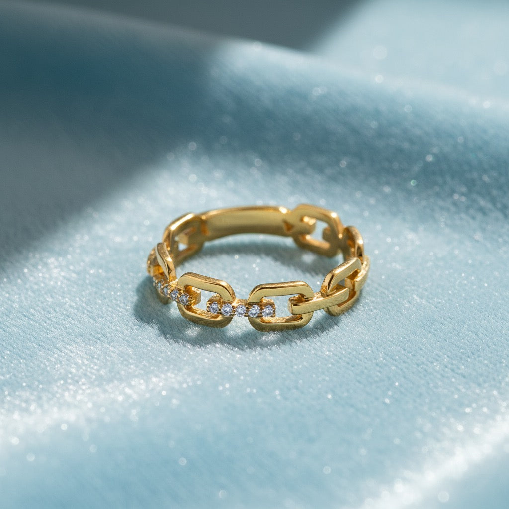 14K yellow gold CZ link ring displayed on soft light blue velvet, highlighting the chain-style design and sparkling stones.
