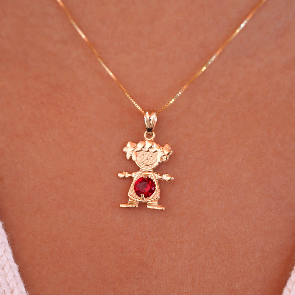 Woman wearing 14K gold girl charm pendant with red cubic zirconia birthstone on a chain necklace.