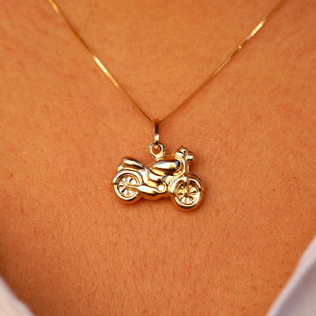 A close-up of a model wearing the 14K gold motorcycle charm pendant on a chain, highlighting its bold design and stylish biker aesthetic.