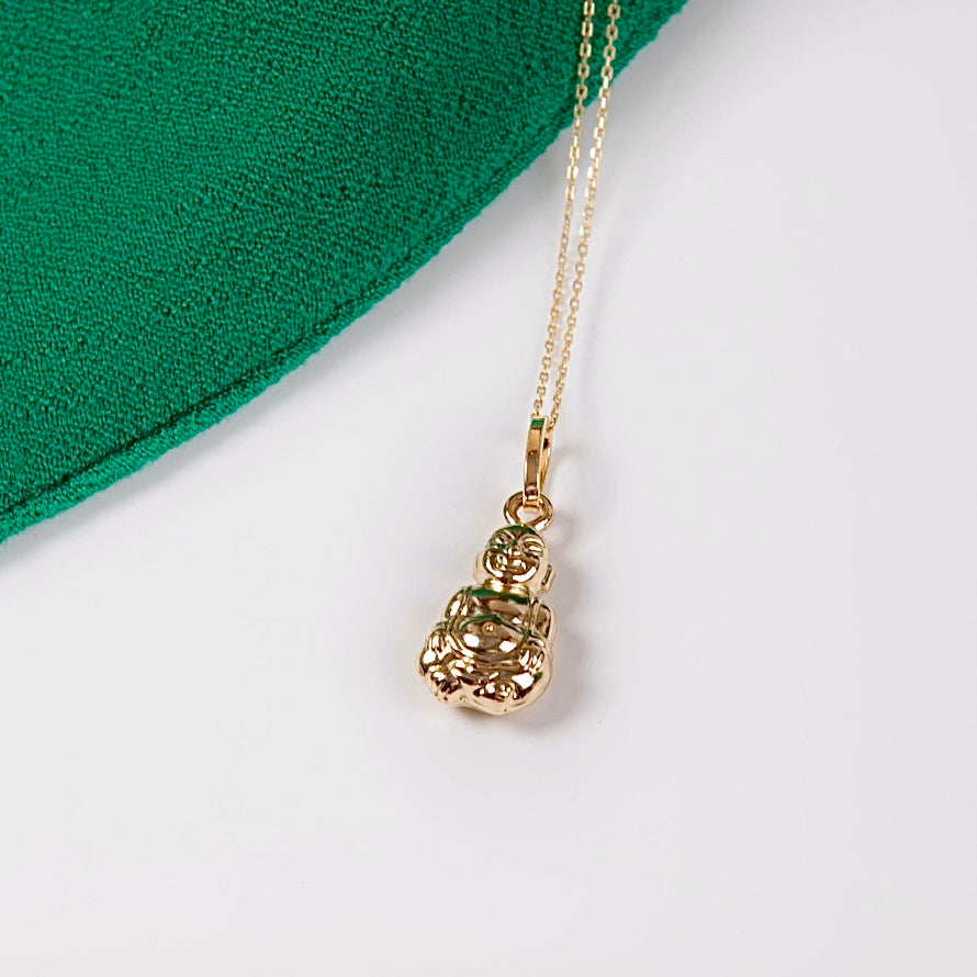 14K Real Gold Buddha Charm resting on a white backdrop, highlighting its polished finish and intricate serene features.