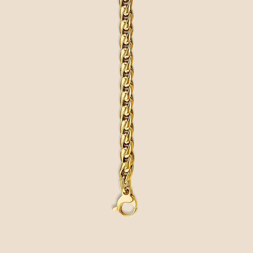 Close-up of 14K gold Franco bracelet resting on a plain background, highlighting the bracelet's polished finish and structured round link pattern.
