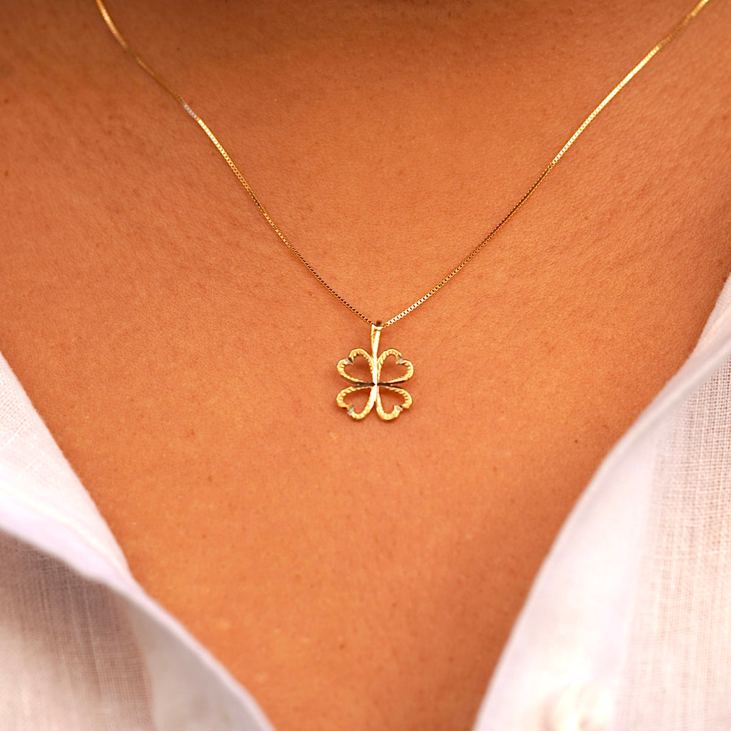 A model wearing the 14K Gold Heart Clover Pendant, showcasing its delicate heart-shaped clover design and radiant yellow gold finish.