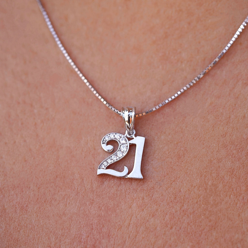 A model wears the 14K white gold "21 Years" charm pendant on a matching white gold chain, with cubic zirconia sparkling subtly under natural light—capturing the elegance and significance of a milestone birthday.