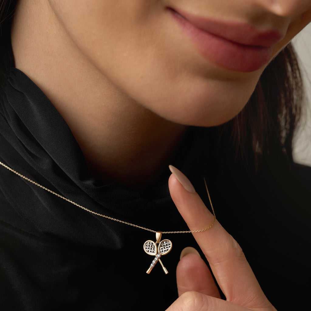A model wearing the 14K Gold Tennis Racquet Pendant, showcasing its detailed two-tone design and sparkling CZ accents. Perfectly sized for layering or wearing alone, it blends sport-inspired charm with timeless elegance.