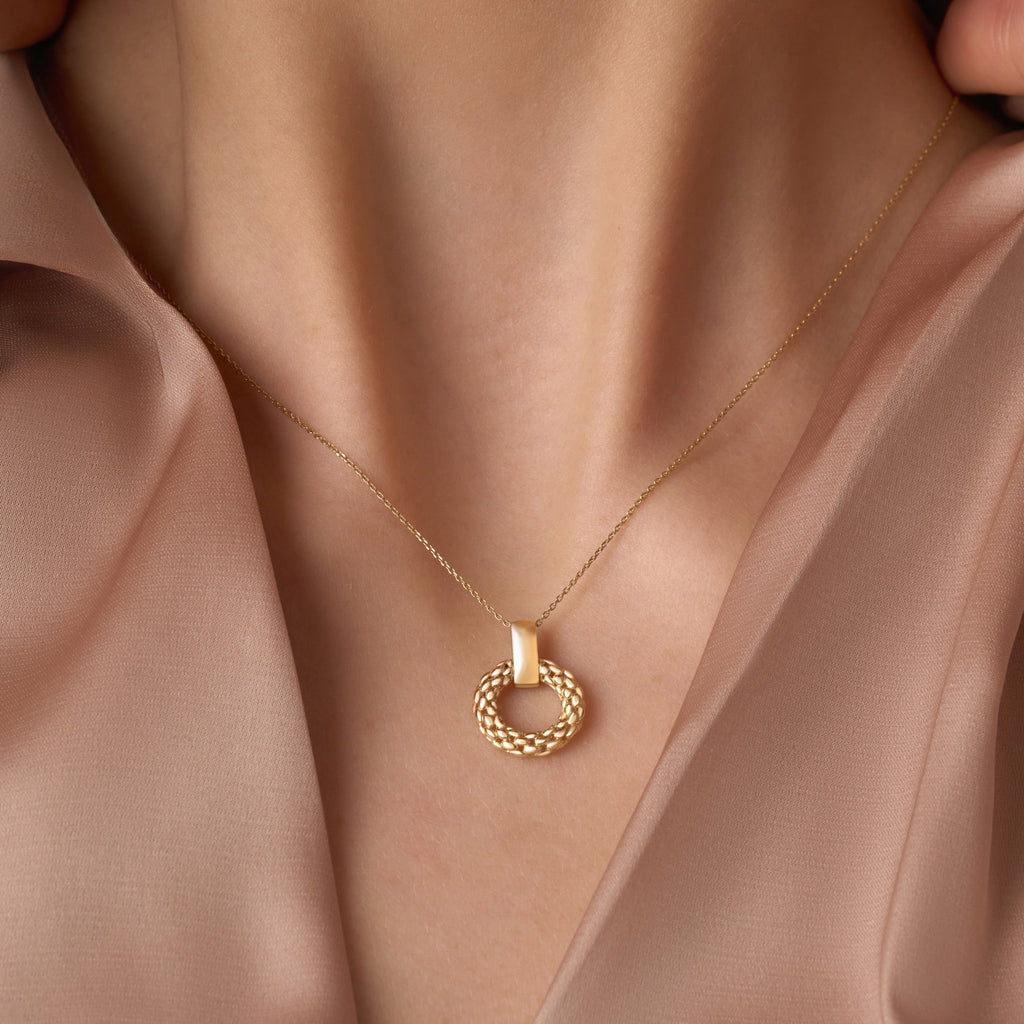 A model wears the 14K gold mesh pendant on a dainty gold chain, the intricate filigree design resting gracefully against her collarbone. The lightweight and elegant pendant adds a timeless touch to her outfit.