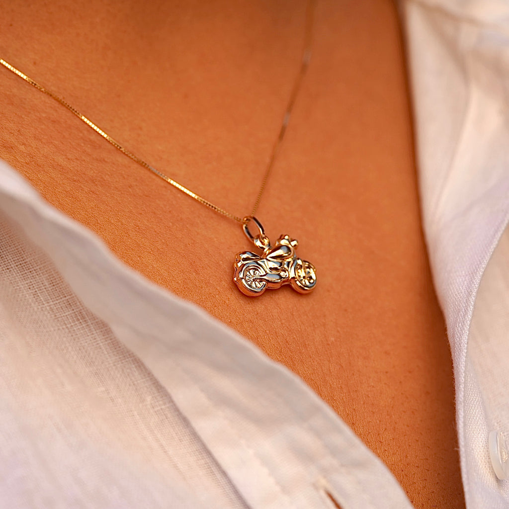 A close-up of a model wearing the 14K gold motorcycle charm pendant on a chain, highlighting its bold design and stylish biker aesthetic.