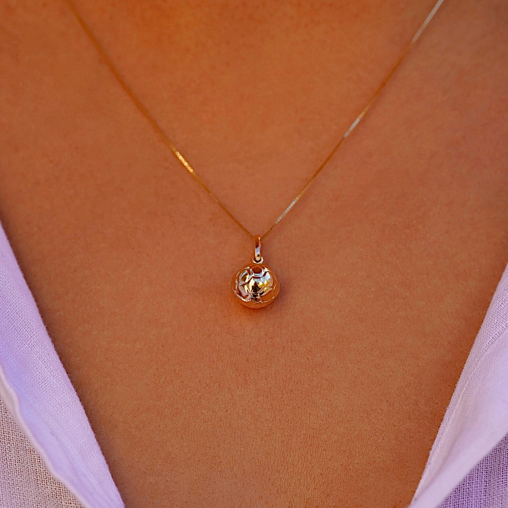 Model wearing 14K yellow gold soccer ball pendant on a thin chain, styled as a sporty-chic necklace.