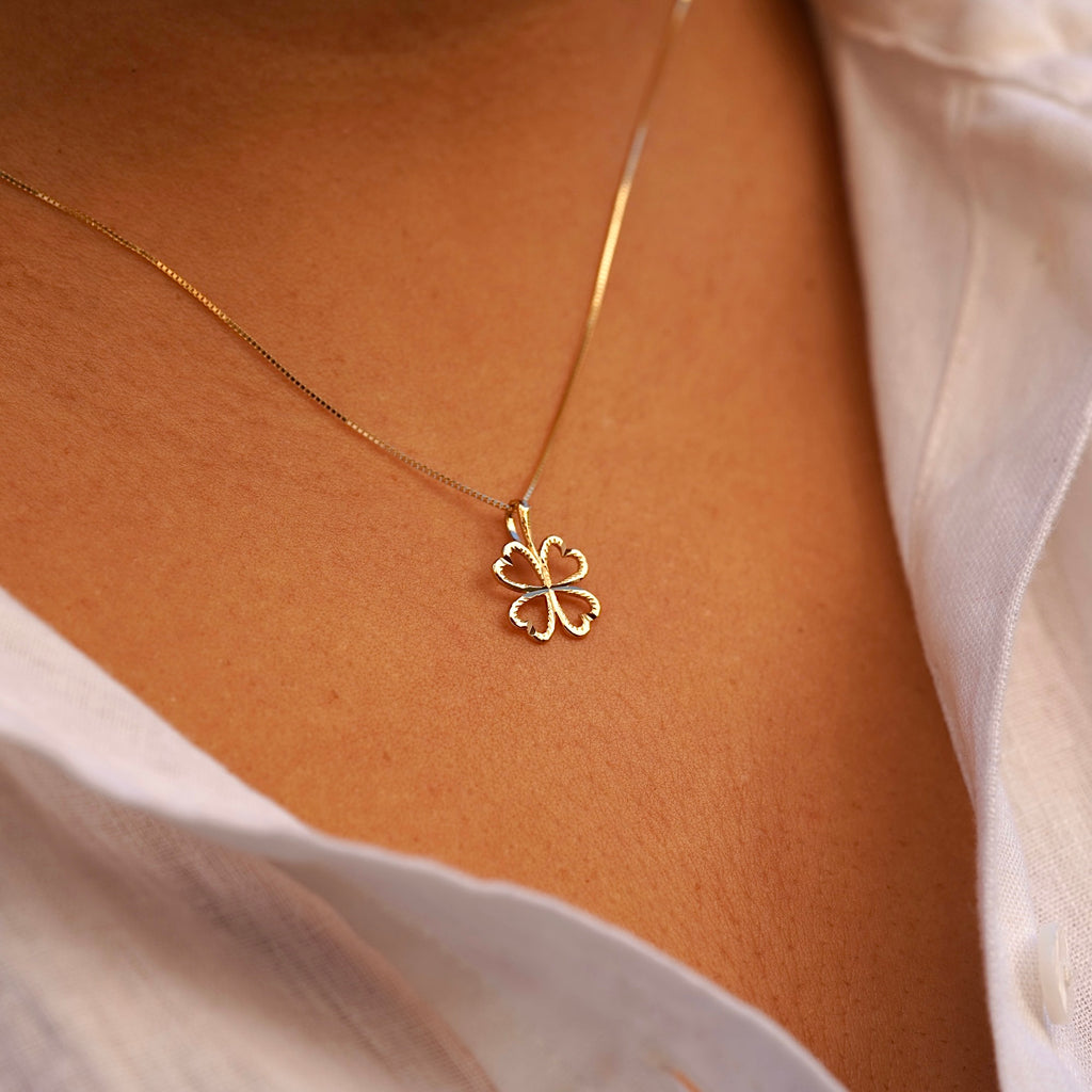 A model wearing the 14K Gold Heart Clover Pendant, showcasing its delicate heart-shaped clover design and radiant yellow gold finish.