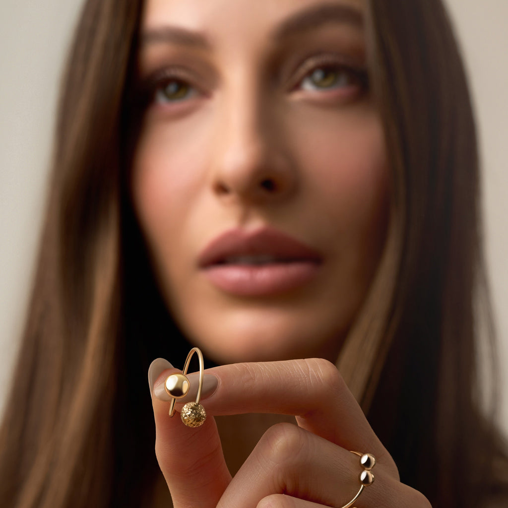 A model’s hand adorned with several rings, featuring the 14K yellow gold polish ball ring with polished beaded detailing. The minimalist, stackable design adds subtle shine and refined elegance, complementing the other rings for a modern, layered look.