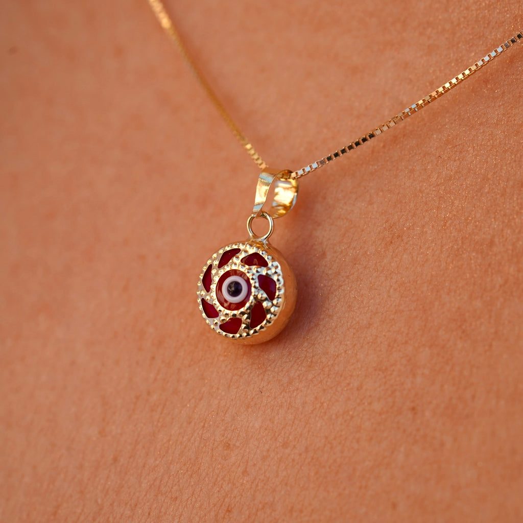 A model is wearing the 14K gold Evil Eye pendant with a red eye on a fine chain, allowing the charm to rest beautifully against the skin. The striking red eye adds a subtle yet meaningful touch, perfect for everyday wear.