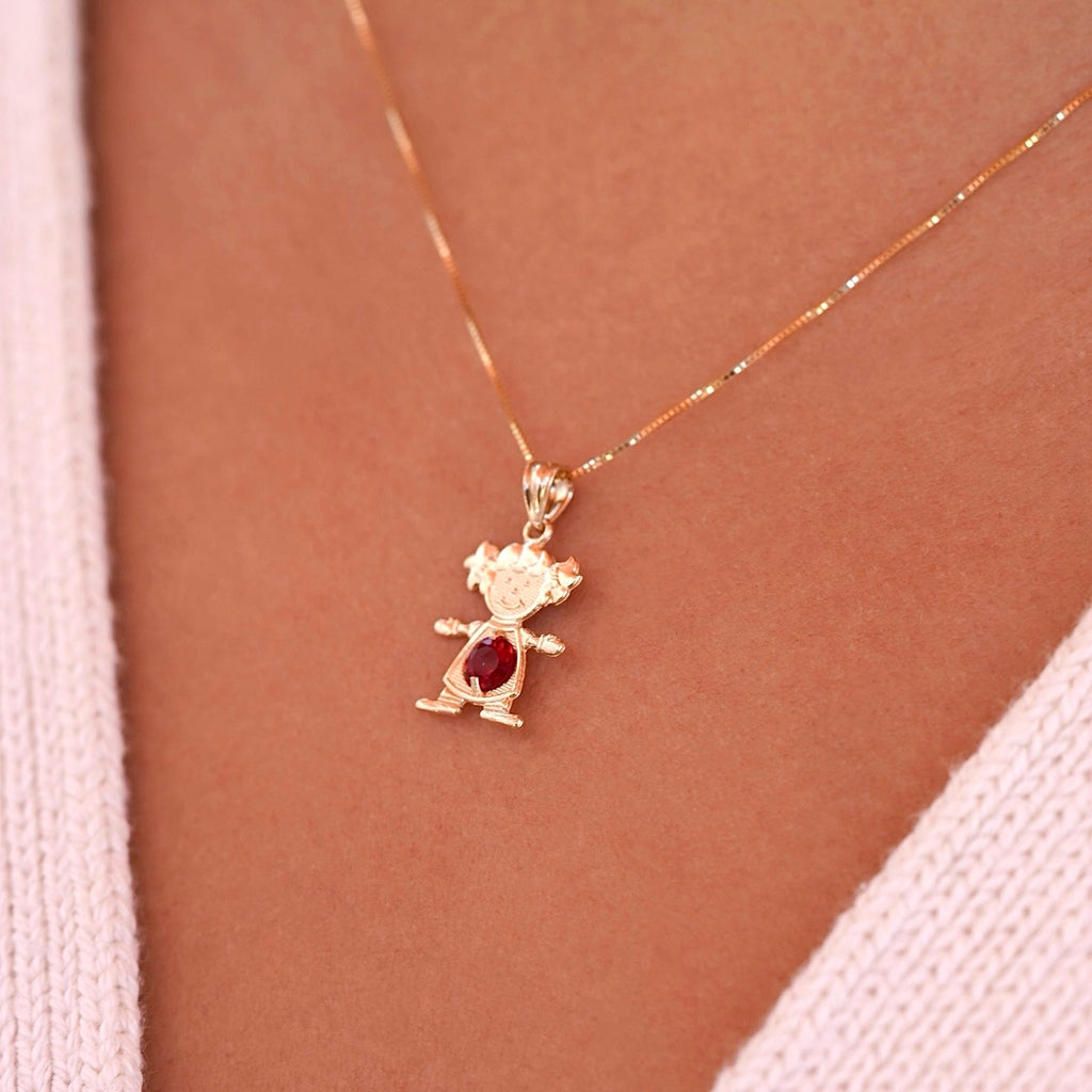 Woman wearing 14K gold girl charm pendant with red cubic zirconia birthstone on a chain necklace.
