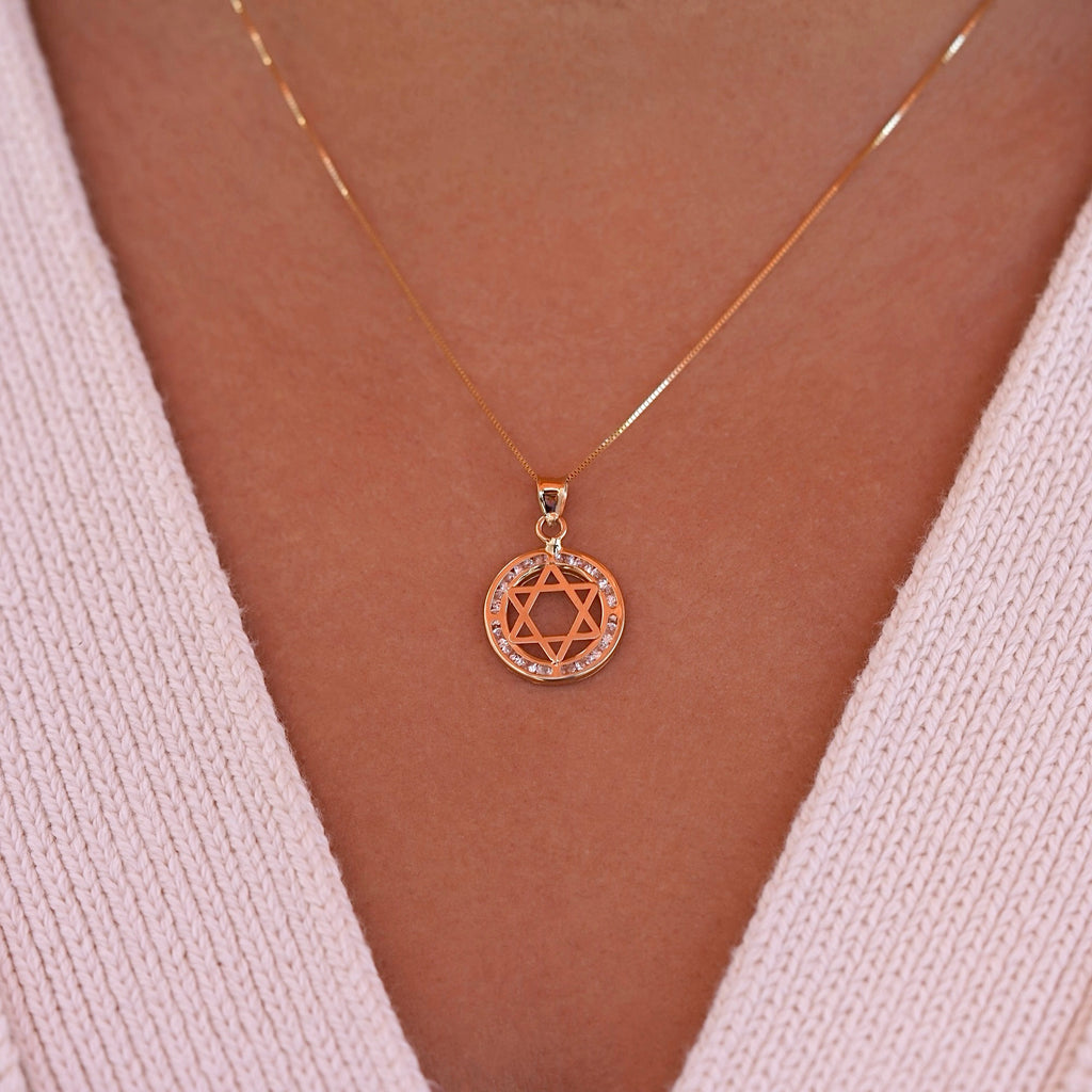 A model wearing the 14K gold Star of David pendant on a delicate gold chain, showcasing how the spiritual charm rests beautifully against the skin, with the CZ stones adding subtle sparkle.